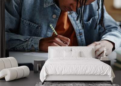 Closeup of black young man writing in notebook at desk in school classroom or in college Wall mural