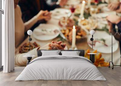 Closeup of people sitting at dining table on Christmas and joining hands in prayer, copy space Wall mural