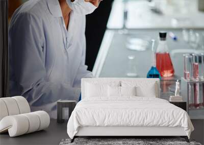 Cropped shot of female microbiologist in medical gloves sitting at workstation observing bacterial colony in petri dish while dripping liquid from pipette in laboratory, copy space Wall mural