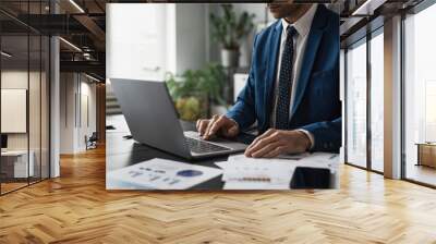 Cropped shot of successful businessman in suit working at able in office and using laptop, copy space Wall mural