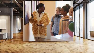 Diverse group of teenagers listening to black woman explaining modern art in museum Wall mural