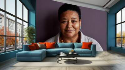 Front view portrait of senior black woman smiling at camera against purple background Wall mural