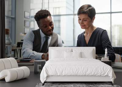 Front view portrait of two successful business people reviewing documents at table in luxury office Wall mural