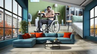 Full length portrait of black man with disability using smartphone and listening to music in modern home, copy space Wall mural