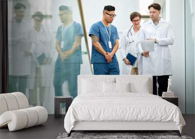 Full length portrait of doctors walking towards camera in hall of modern clinic and holding clipboards, copy space Wall mural