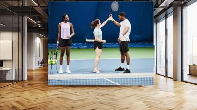 Full length portrait of female tennis coach working with African American man during practice at indoor court Wall mural