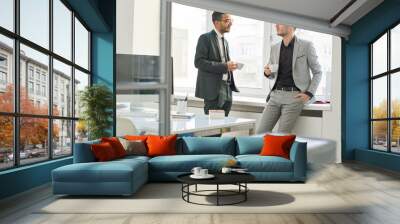 Full length portrait of two young business people chatting during coffee break, one of them Middle-Eastern Wall mural