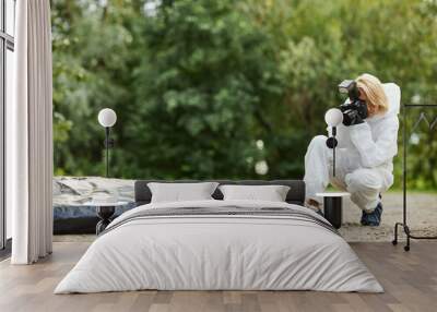 Full length portrait of woman wearing protective suit and taking photographs at crime scene outdoors, copy space Wall mural