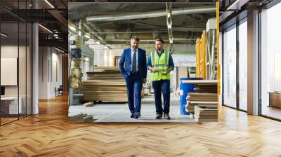 Full length portrait of young workman giving tour of modern factory to handsome mature businessman discussing possible investment, copy space Wall mural