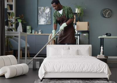 Full length side view of adult African American man mopping floors in office and enjoying Spring cleaning at workplace, copy space Wall mural