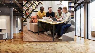 Full length view at diverse group of young people studying together at table in college library, copy space Wall mural