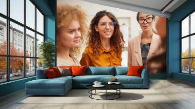 Group of four cheerful young women chatting during break, horizontal shot Wall mural