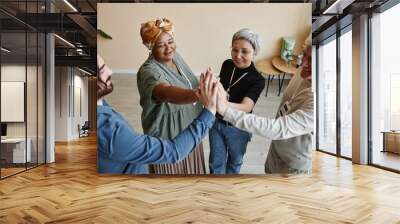 Group of senior people high five while celebrating success togethet Wall mural