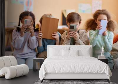 Group of young children holding smartphones and hiding faces, gen Alpha Wall mural