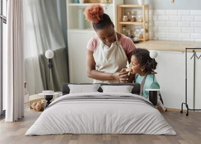 Happy mother and daughter tasting fresh homemade cookies Wall mural