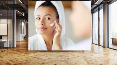 Head and shoulders portrait of  beautiful Mixed-Race woman applying face cream during morning routine, copy space Wall mural