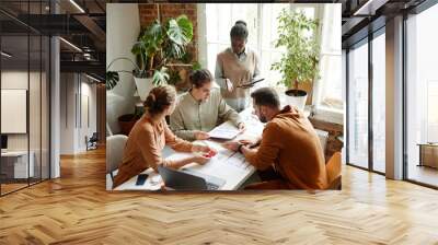 High angle portrait of creative team using laptop while discussing design project in studio, copy space Wall mural