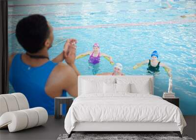 High angle portrait of three mature women doing aqua aerobics in swimming pool with fitness instructor, copy space Wall mural