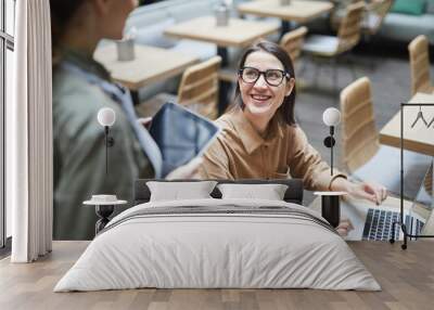 High angle portrait of young woman looking at waitress and smiling while working in cafe , copy space Wall mural