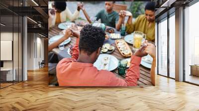 High angle view at African American family saying grace at table outdoors and holding hands during gathering Wall mural