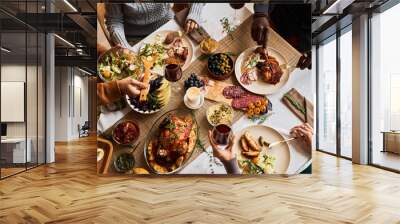 High angle view at diverse group of friends enjoying homemade food at festive dinner table with roasted turkey or chicken, copy space Wall mural