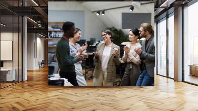 High angle view at multi-ethnic group of business people smiling cheerfully while chatting during coffee break in office, copy space Wall mural