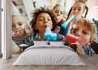 High angle view at multi ethnic group of children blowing party horns at camera Wall mural