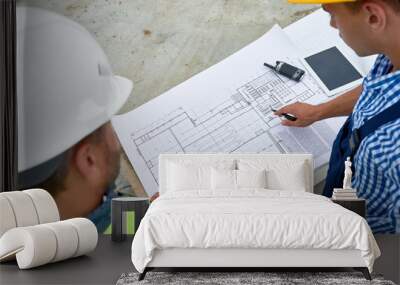 High angle view at  two construction workers discussing floor plans and engineering documentation on site Wall mural