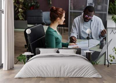 High angle view at two people discussing project and reading documents at workplace in office decorated with plants Wall mural