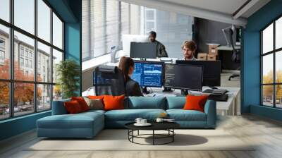 High angle view at young IT developers working with multiple computer monitors in open office copy space Wall mural