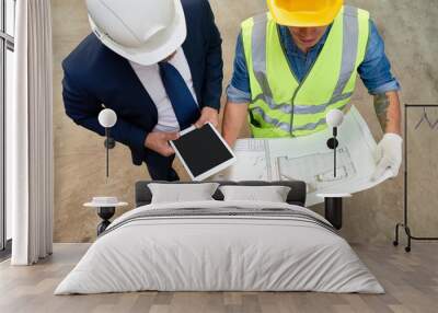 High angle view of unrecognizable foreman and architect studying blueprint while having working meeting at construction site Wall mural