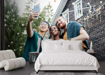 Low angle portrait of multiethnic group of adult friends taking selfie together outdoors in house yard decorated with fairy lights copy space Wall mural