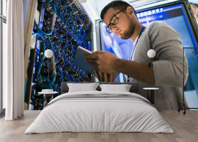 low angle portrait of young man using digital tablet standing by server cabinet while working with s Wall mural