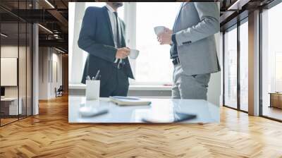 Mid-section portrait of two successful business people holding cups and chatting during coffee break in modern office Wall mural