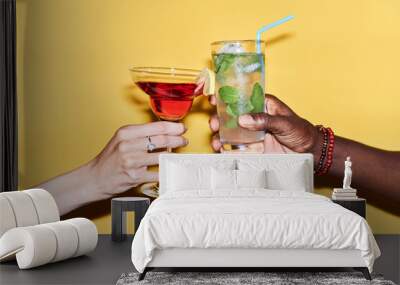 Minimal close up of multiethnic couple clinking cocktails against vibrant yellow background Wall mural