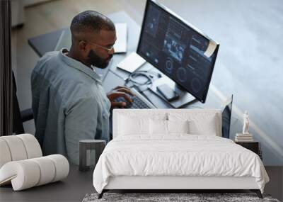 Minimal high angle view at African American software developer working with computers and data systems in office Wall mural