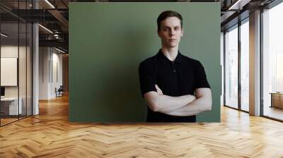 Minimal portrait of confident young man looking at camera against green, copy space Wall mural