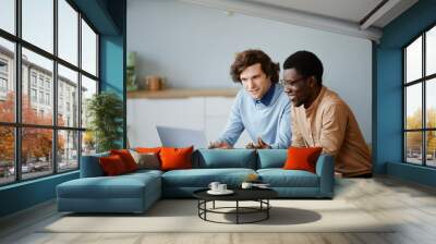 Minimal portrait of two young men using laptop together while working on project in software development office, copy space Wall mural