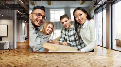 Multi-ethnic group of cheerful students looking at camera and smiling sitting at desk in lecture hall of modern college Wall mural