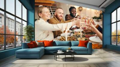 Multi-ethnic group of people raising glasses while celebrating Christmas with friends and family sitting at beautiful dinner table Wall mural