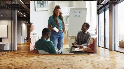 Multi-ethnic group of people sitting in circle while discussing business project in office, focus on smiling African-American woman talking to colleagues, copy space Wall mural