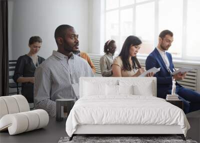 Multi-ethnic group of people sitting on chairs in audience at business conference or seminar and taking notes, copy space Wall mural