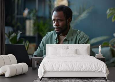 Portrait of adult African American man using computer at workplace in office decorated with green live plants copy space  Wall mural