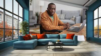 Portrait of adult African-American man using wheelchair while working from home and looking at camera, copy space Wall mural