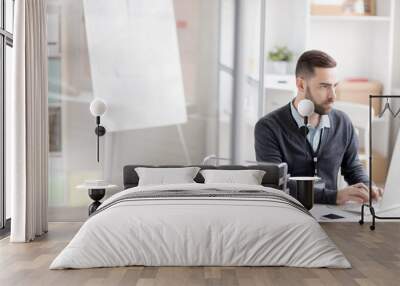 Portrait of bearded businessman using computer while working at desk in modern office, copy space Wall mural