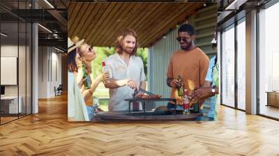 Portrait of bearded young man grilling meat outdoors with diverse group of friends at barbeque party in Summer Wall mural