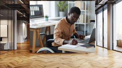 Portrait of black young man with disability working in office and using laptop, accessible workplace concept Wall mural