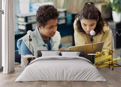 Portrait of boy and girl using laptop together and programming robots during engineering class at school Wall mural