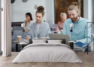 Portrait of contemporary bearded man using laptop in class with group of students enjoying lecture, copy space Wall mural