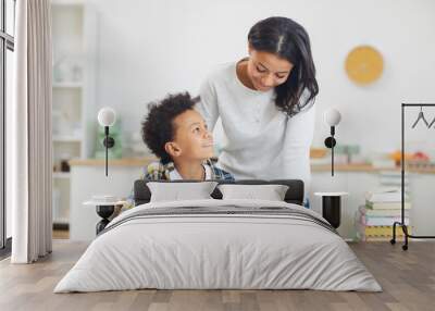 Portrait of cute African-American boy smiling at mother while studying at home in minimal white interior, copy space Wall mural